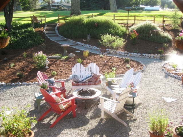 A gravel patio features Adirondack chairs and a fire pit.